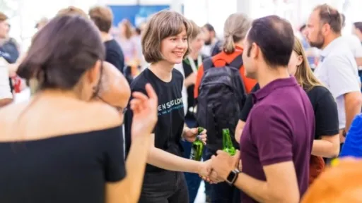 A group of people happily meet and shake hands at a crowded event.