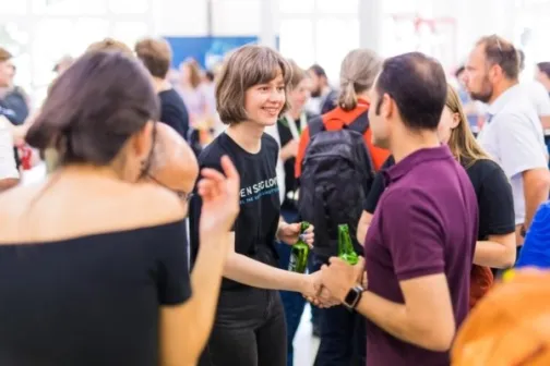 A group of people happily meet and shake hands at a crowded event.