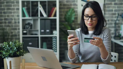 Girl looking at phone and bank card