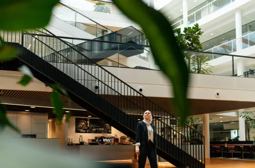 Woman in black suit standing in sunlit office