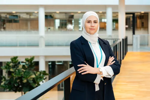 Woman in black suit standing in sunlit office