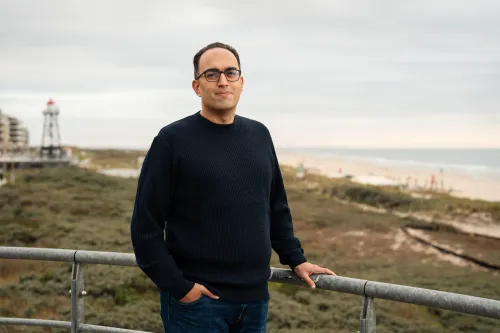 Man standing with dunes in background against cloudy sky
