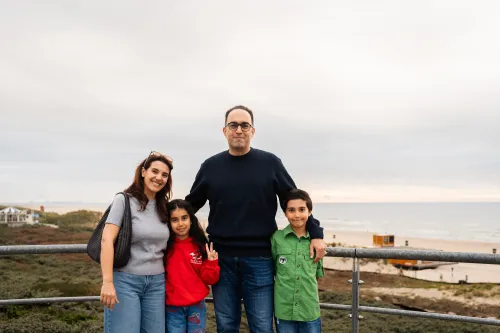 A family posing in front of the beach.